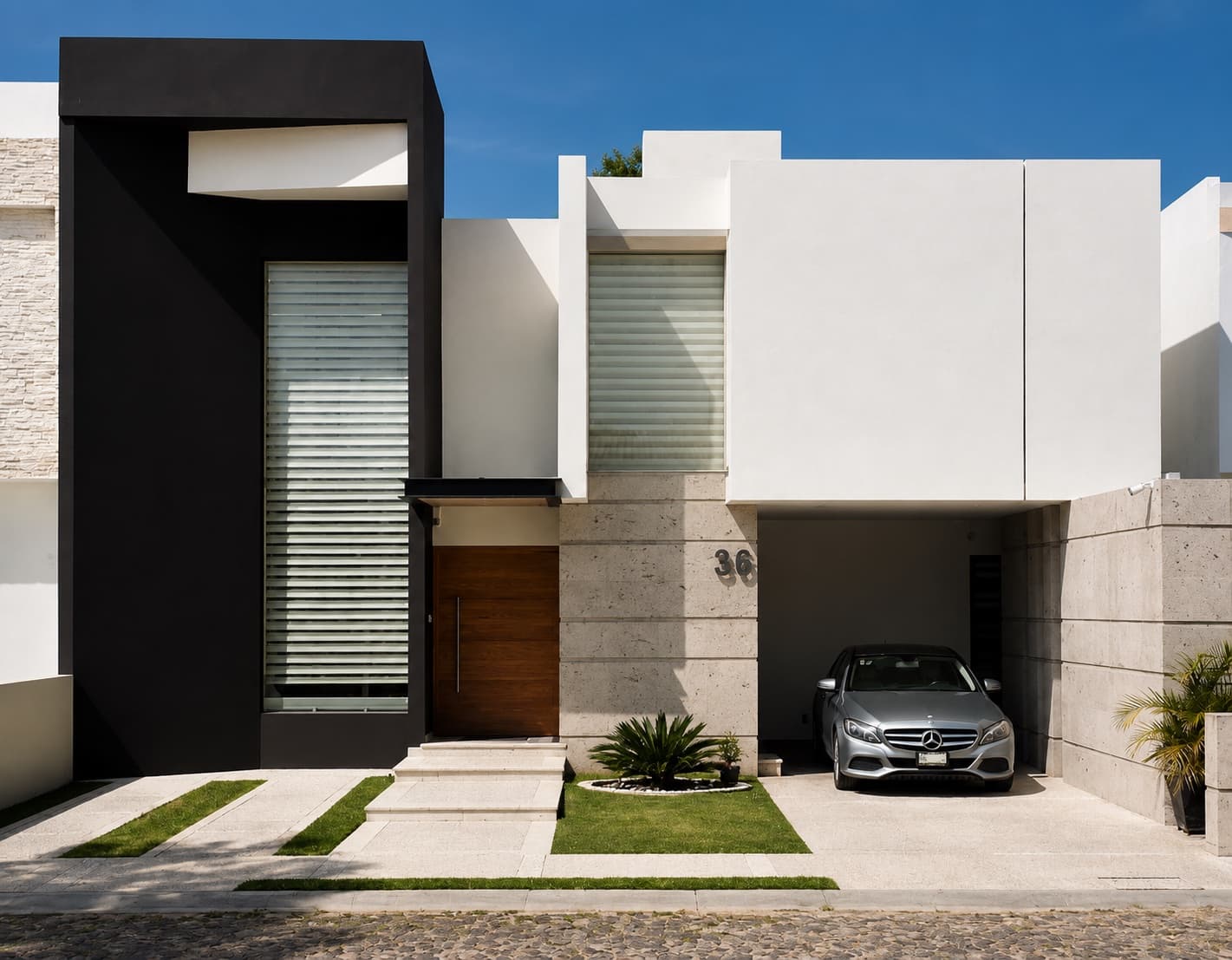 Fachada contemporánea blanca de Casa Eugenia, con un volumen negro y cochera, en Tequisquiapan