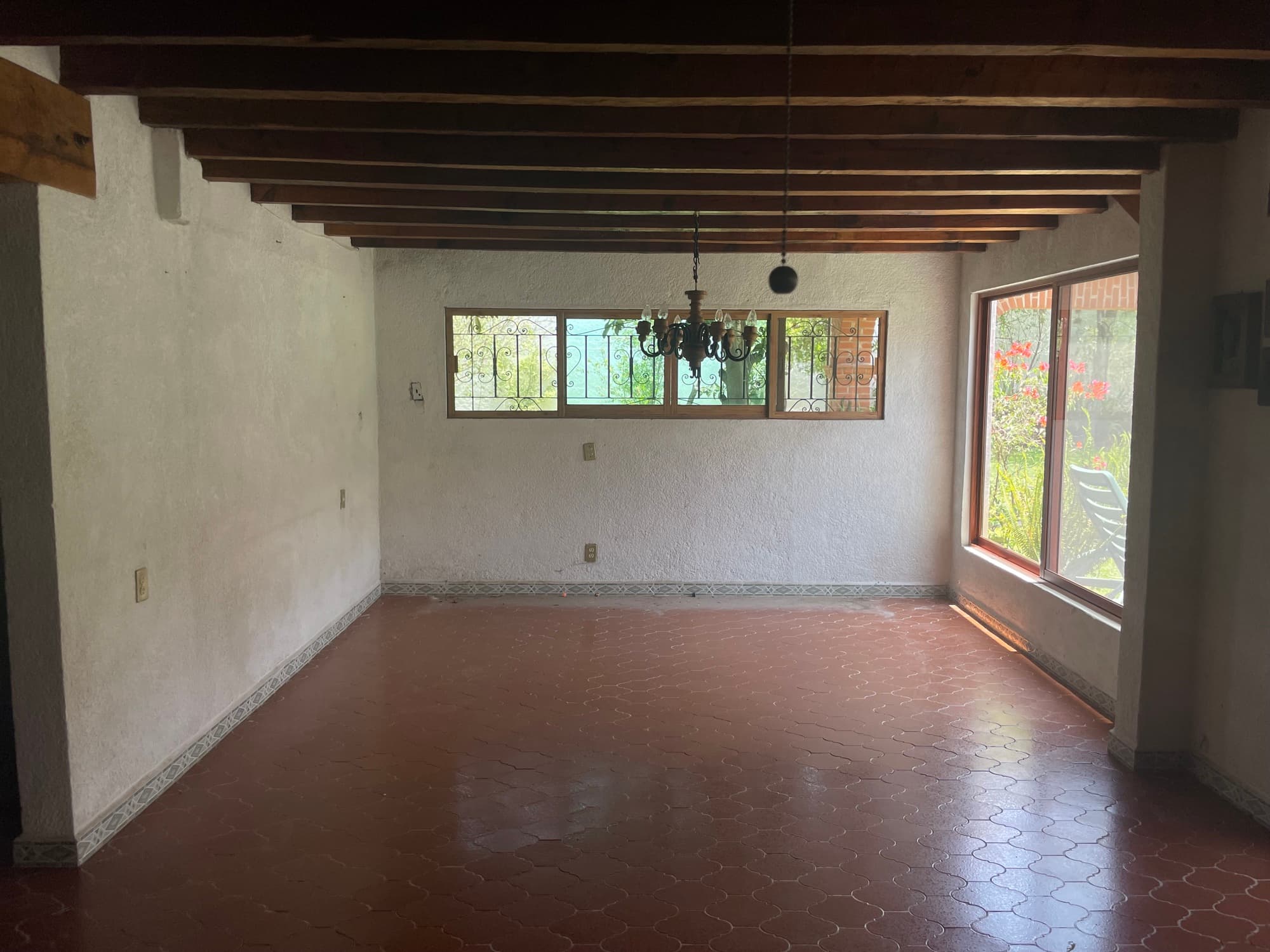 Antes de la remodelación: estancia vacía con piso de barro y techo de vigas